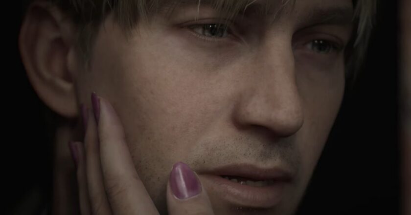 A hand with pink nail polish gently cradling the face of James Sunderland in official art from the Silent Hill 2 remake, the flagship of the horror franchise’s comeback first wave as Konami producer Motoi Okamoto confirms ‘second and third waves’ of new Silent Hill games are already in planning